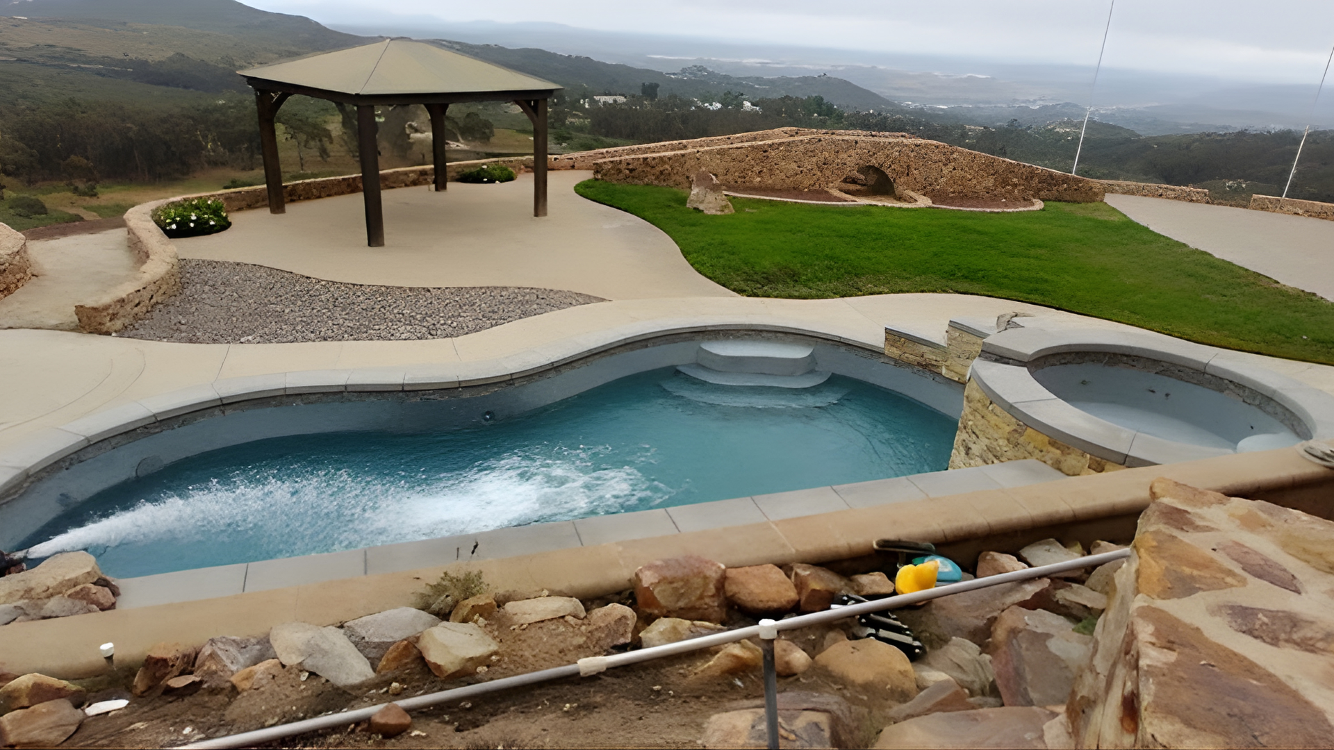 A white water truck parked on a dirt lot against a backdrop of hills, with a logo visible on the tank.