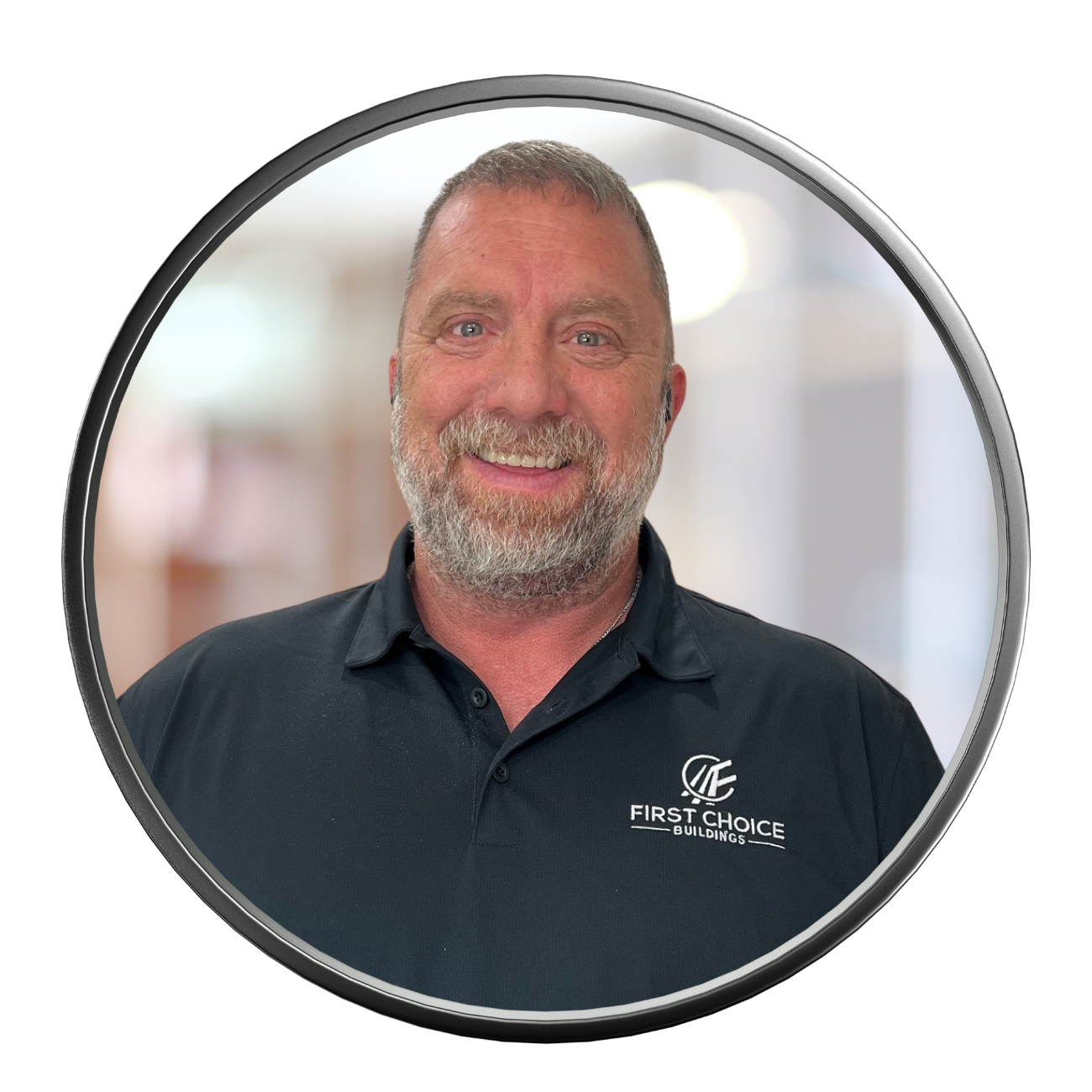 Man with a beard wearing a black polo shirt smiling, the logo on the shirt says