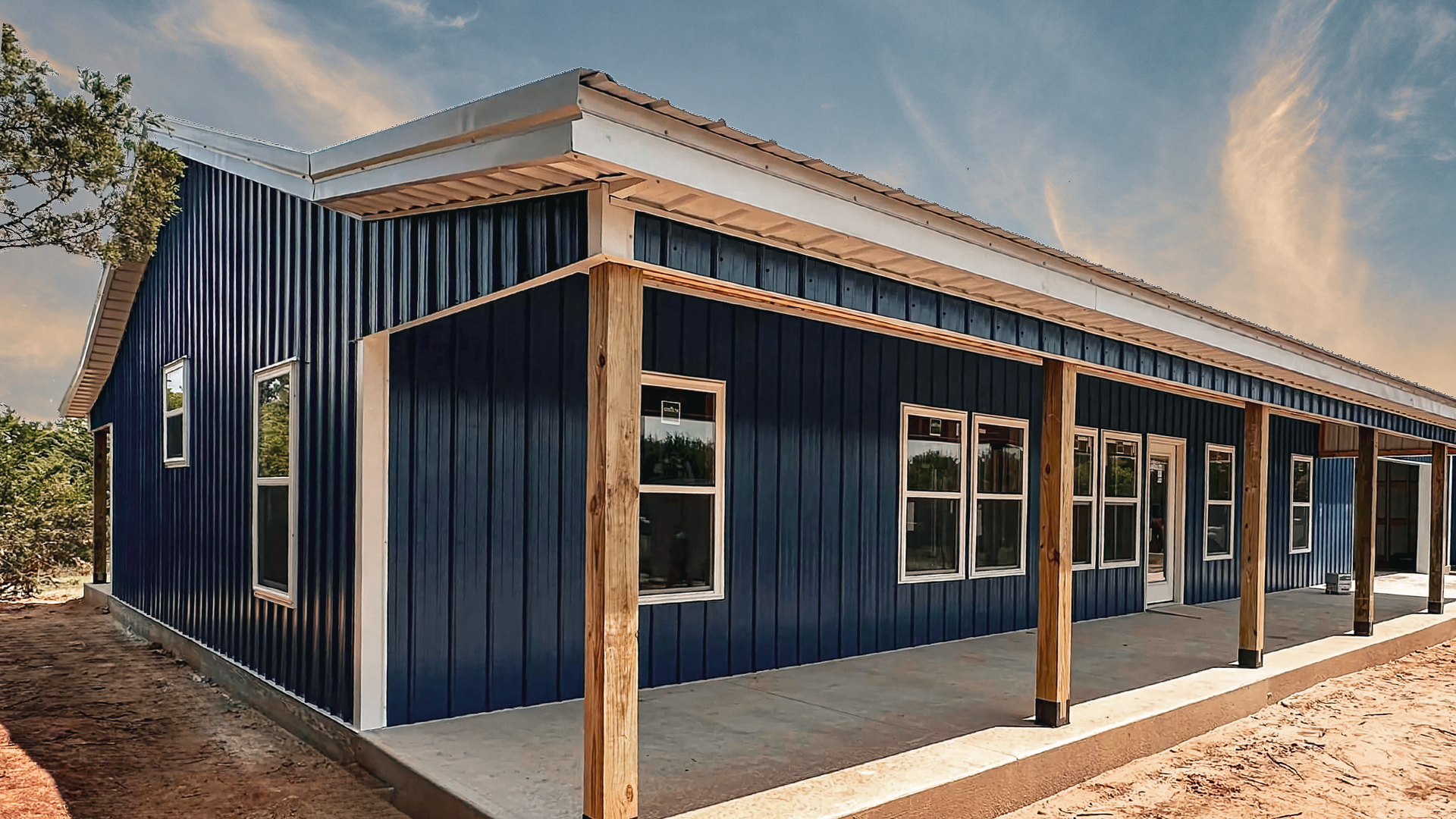 White and blue building with open garage and porch, under a bright blue sky.