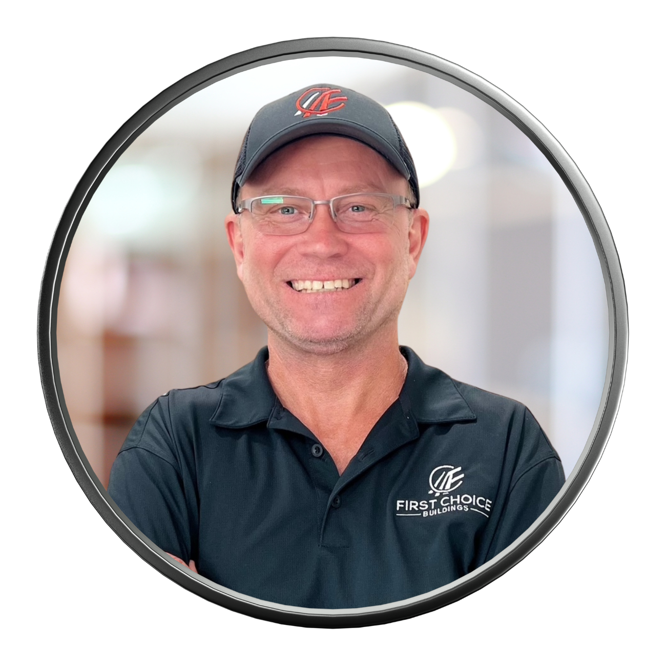 Man smiling, wearing glasses and a baseball cap with logo; wearing a polo shirt with logo; round frame.