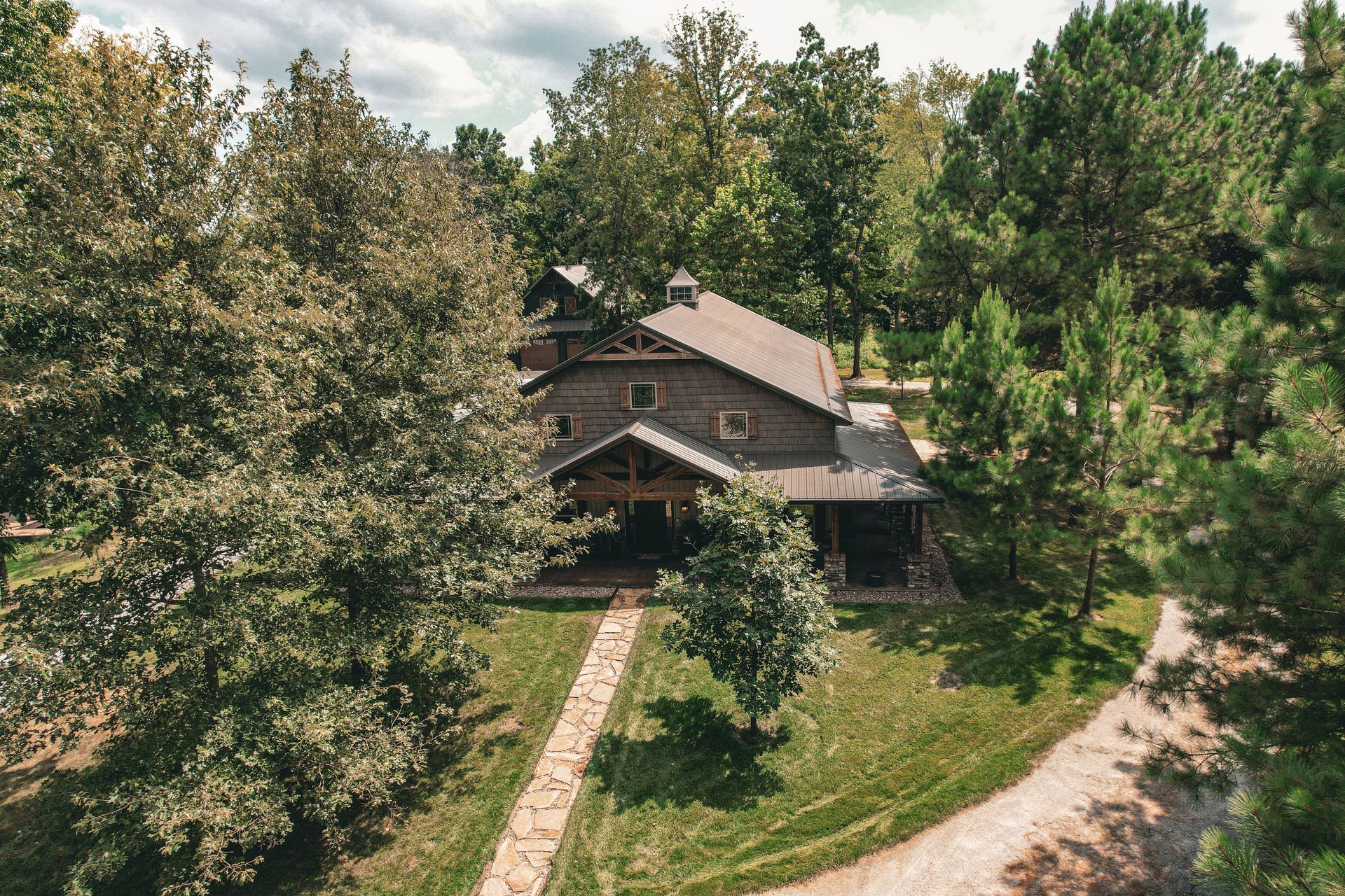 Wooden building nestled among trees with a stone path leading to the entrance.