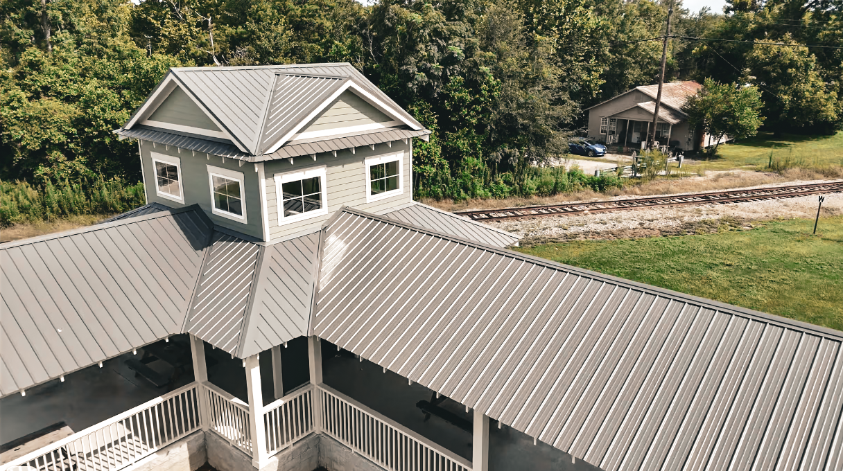 A new two-car garage with a brown metal roof, white doors, and a small tree in front.