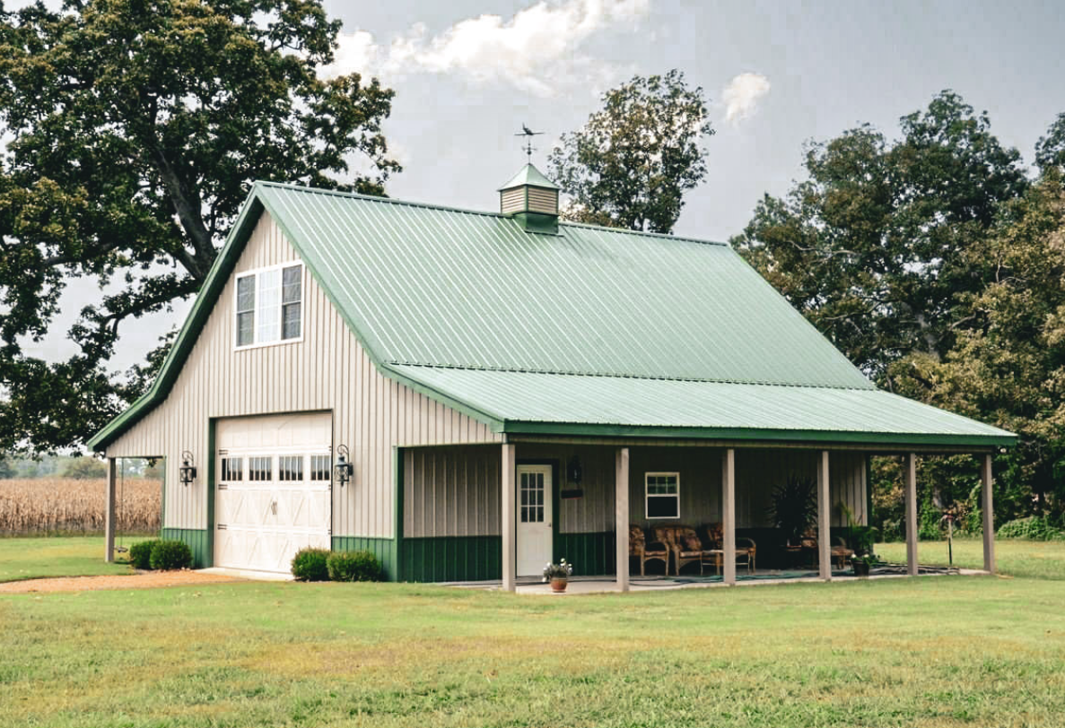 Red metal barn with two garage doors, men, truck, ATV on gravel driveway.