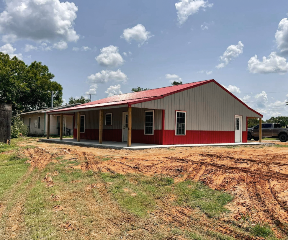 White and black metal garage with two bays and a small porch under a blue sky.