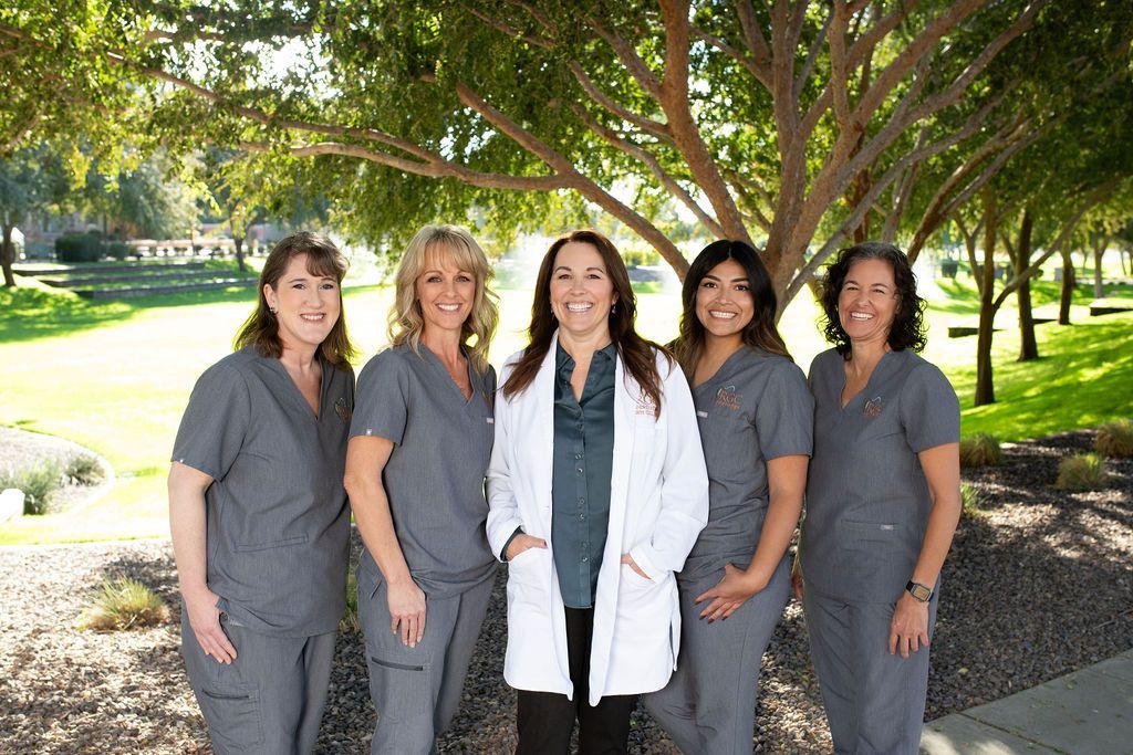 A group of nurses are posing for a picture in front of a tree.
