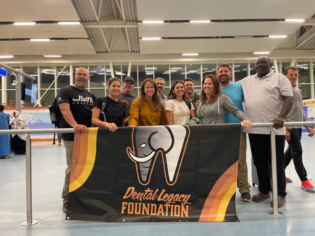 A group of people are standing in front of a dental legacy foundation banner.