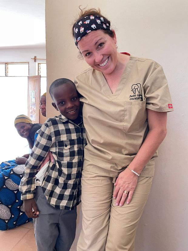 A woman in scrubs is posing for a picture with a young boy in a plaid shirt.