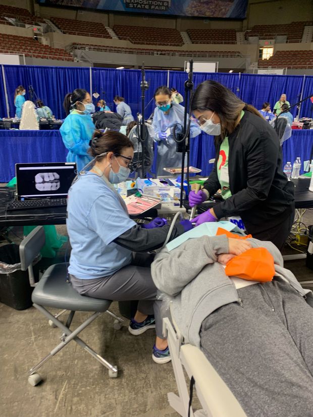 A group of dentists are working on a patient in a dental office.