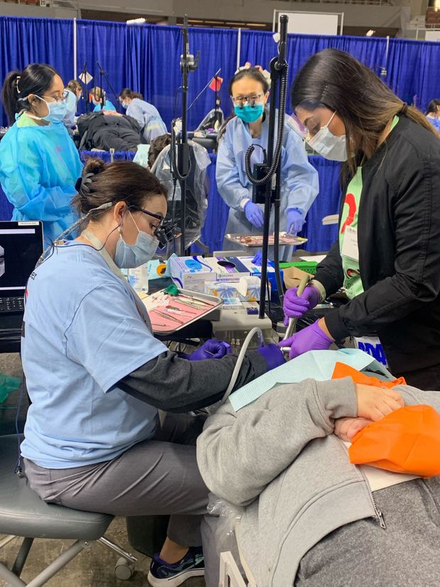 A group of dentists are working on a patient in a dental office.