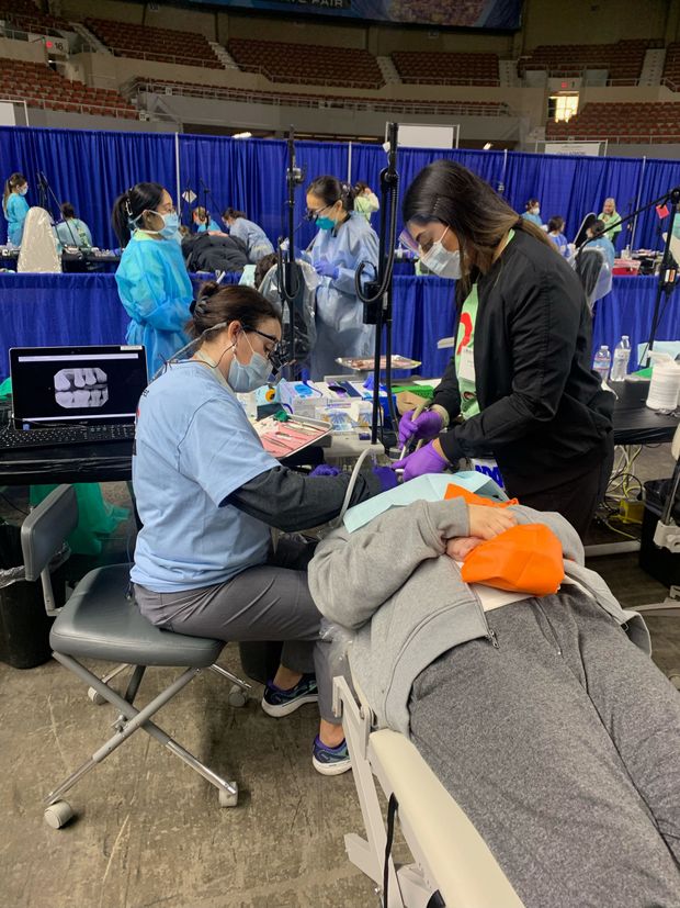 A dentist is examining a patient 's teeth in a dental office.