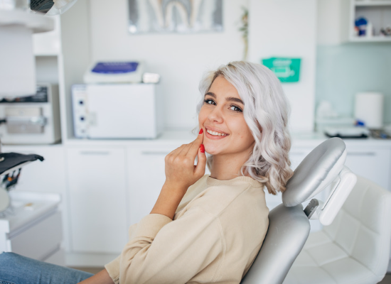 A woman is sitting in a dental chair and smiling.