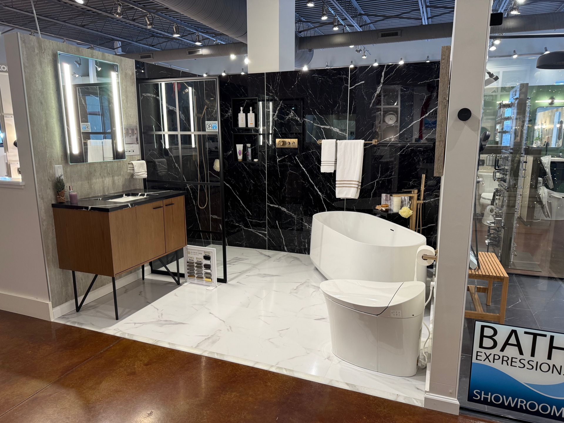 Bathroom showroom with black marble wall, white tub, and wood vanity.