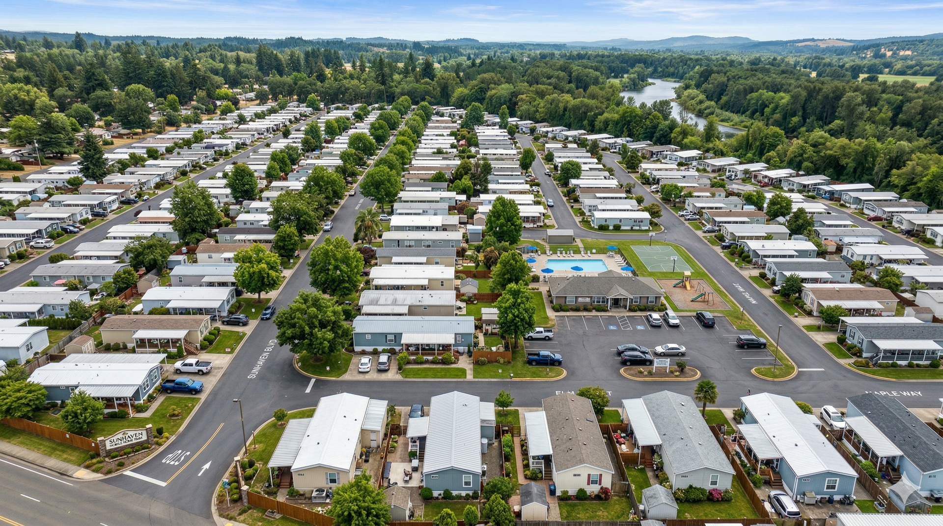 Aerial view of a dense residential mobile home park with rows of houses, trees, a community pool, and paved streets.