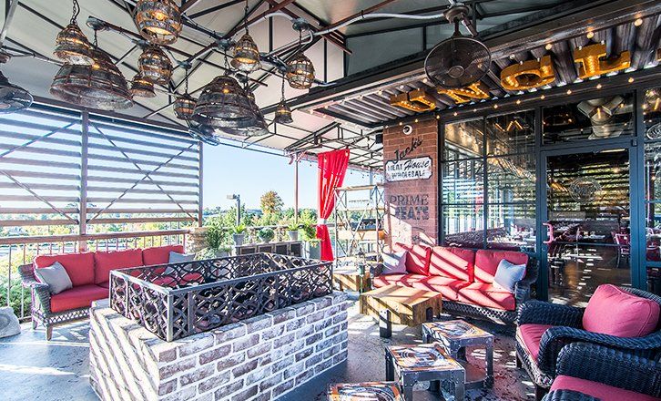 a patio with a fire pit , couch , chairs and tables  at uncle jacks meathouse duluth