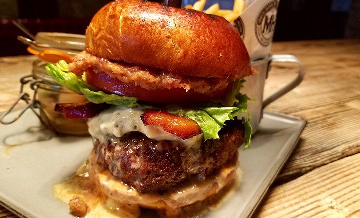 a close up of a hamburger with lettuce and bacon on a plate