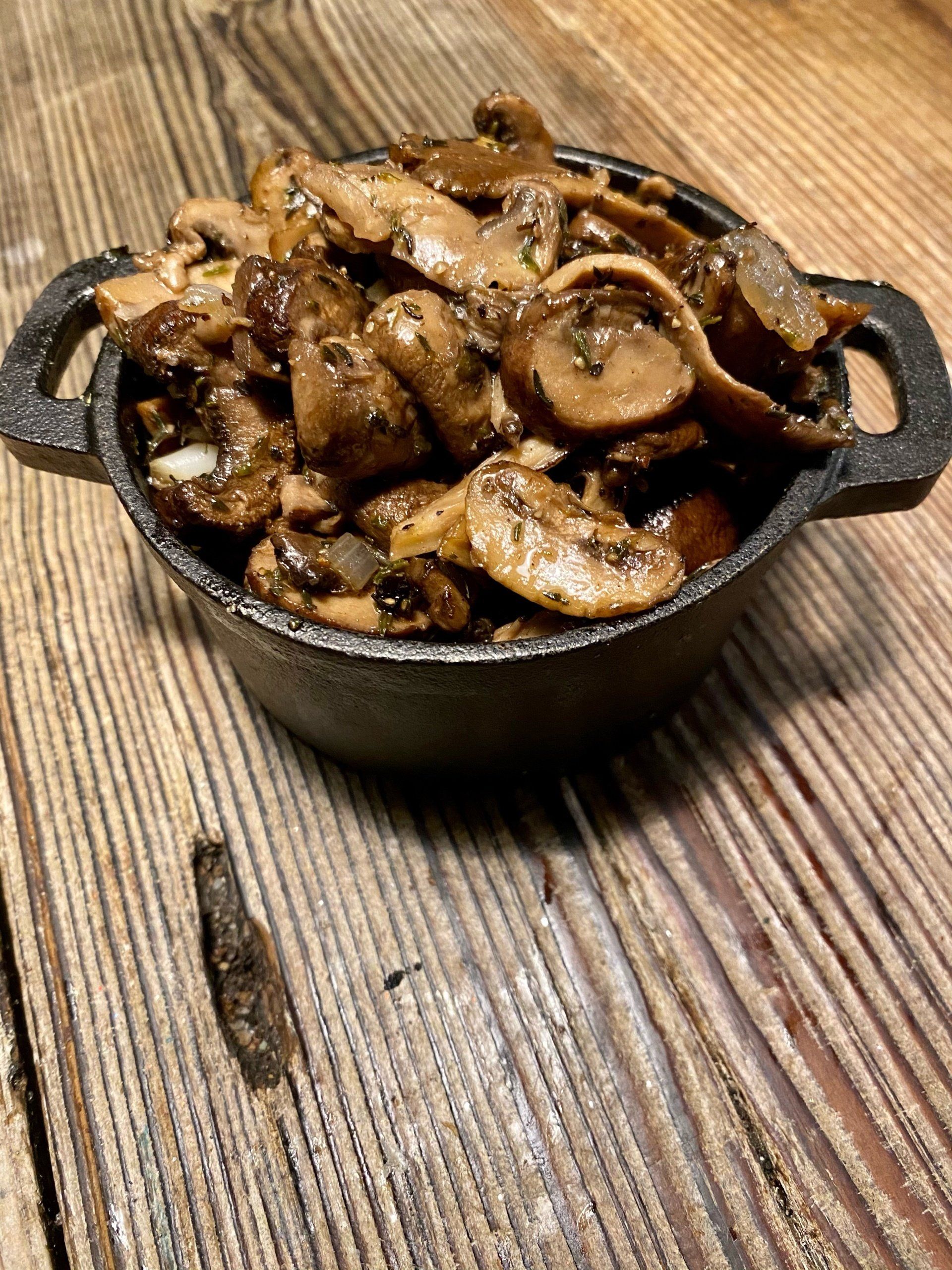 a bowl of mushrooms sits on a wooden table