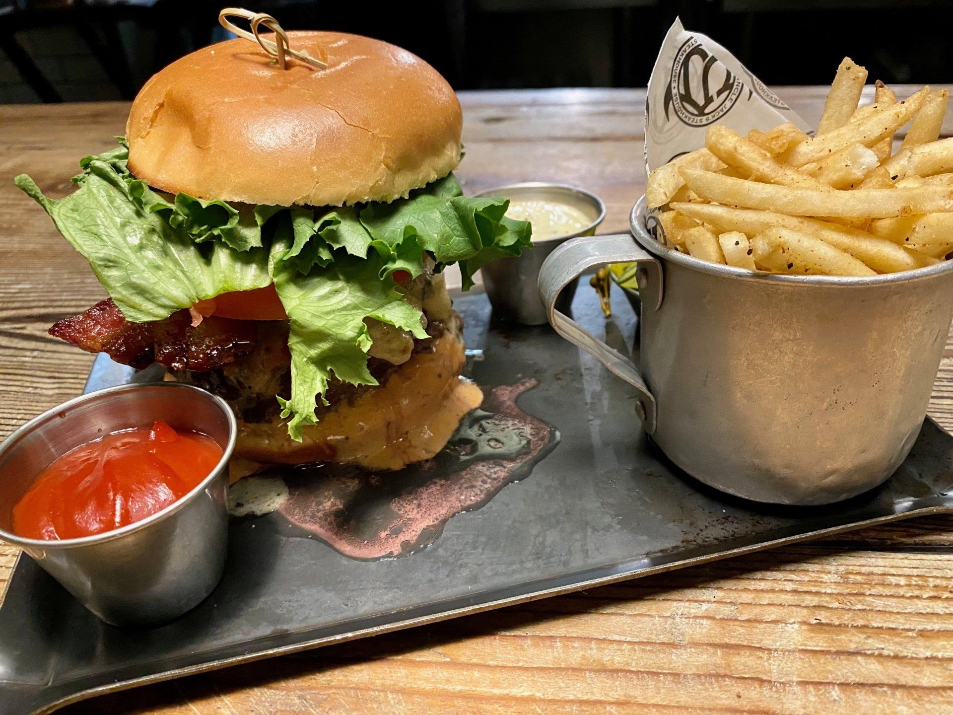 a hamburger and french fries on a tray with ketchup and mustard