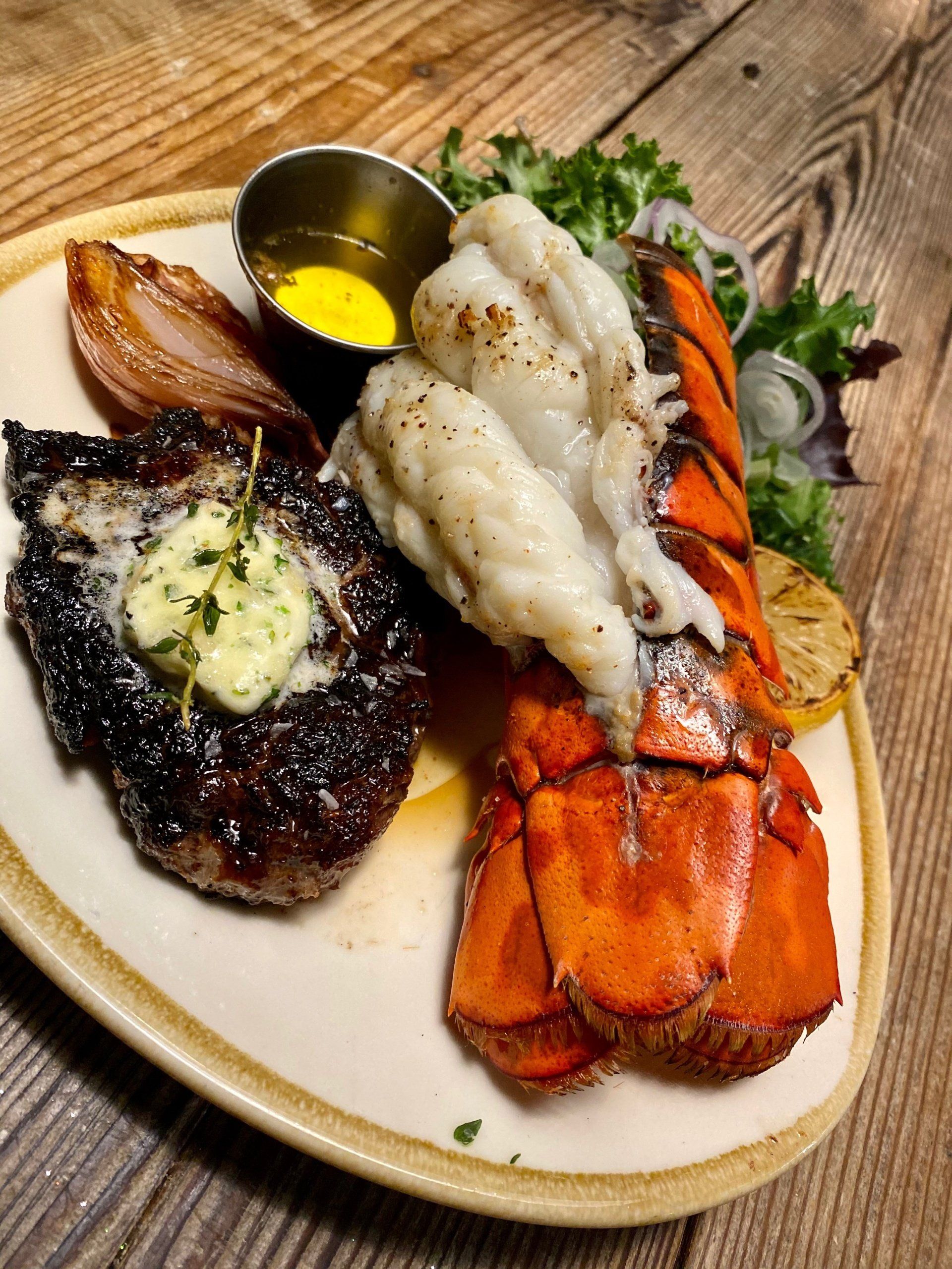 a white plate topped with a steak and a lobster tail
