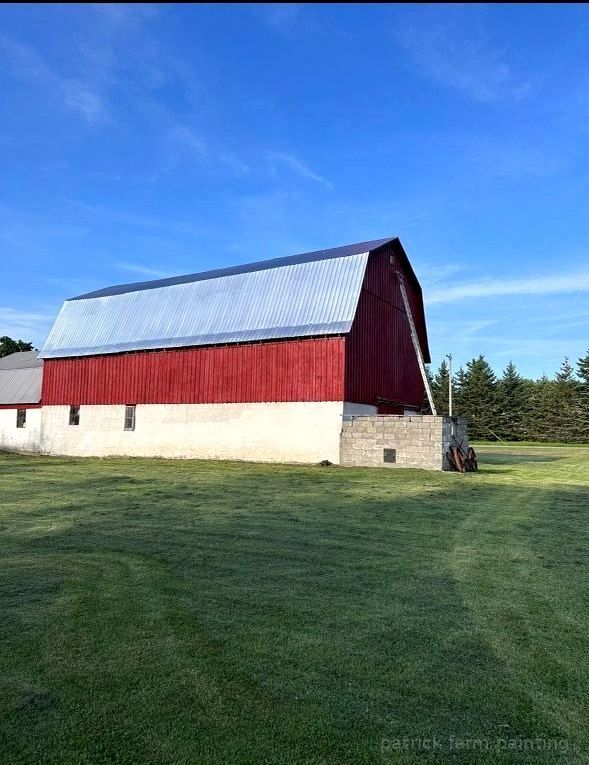 Barn painting services by Patrick Farm Painting in Boonville, New York. This image features a professionally restored barn or farmhouse surrounded by peaceful countryside scenery, open farmland, and natural outdoor lighting. The freshly painted siding, trim, and exterior surfaces highlight the craftsmanship of experienced barn painters and the trusted farm painting guy from Patrick Farm Painting, a company that paints barns in New York. The building appears clean, durable, and visually refreshed with smooth finishes and vibrant color restoration. This detailed description helps visually impaired website visitors imagine the rural setting, the scale of the agricultural structure, and the quality transformation completed during the farm painting project.