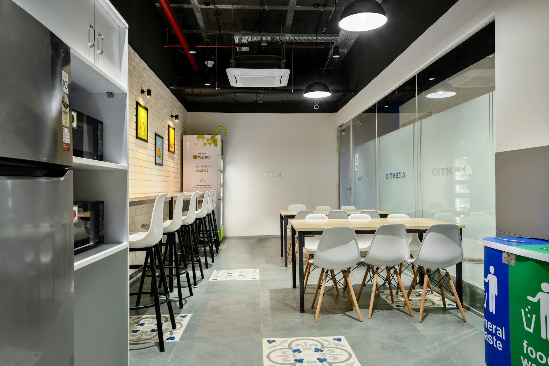 An office breakroom with a refrigerator, bar, tables, and chairs. White and gray colors dominate the space.