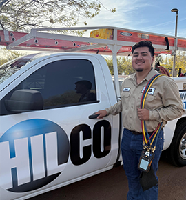HVAC technician stands by a work truck with