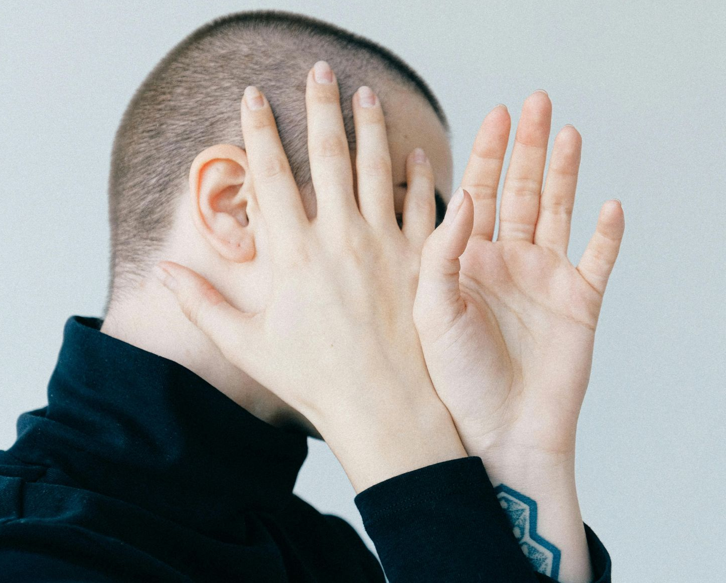 Person verdeckt ihr Gesicht, da sie nicht fotografiert werden möchte.