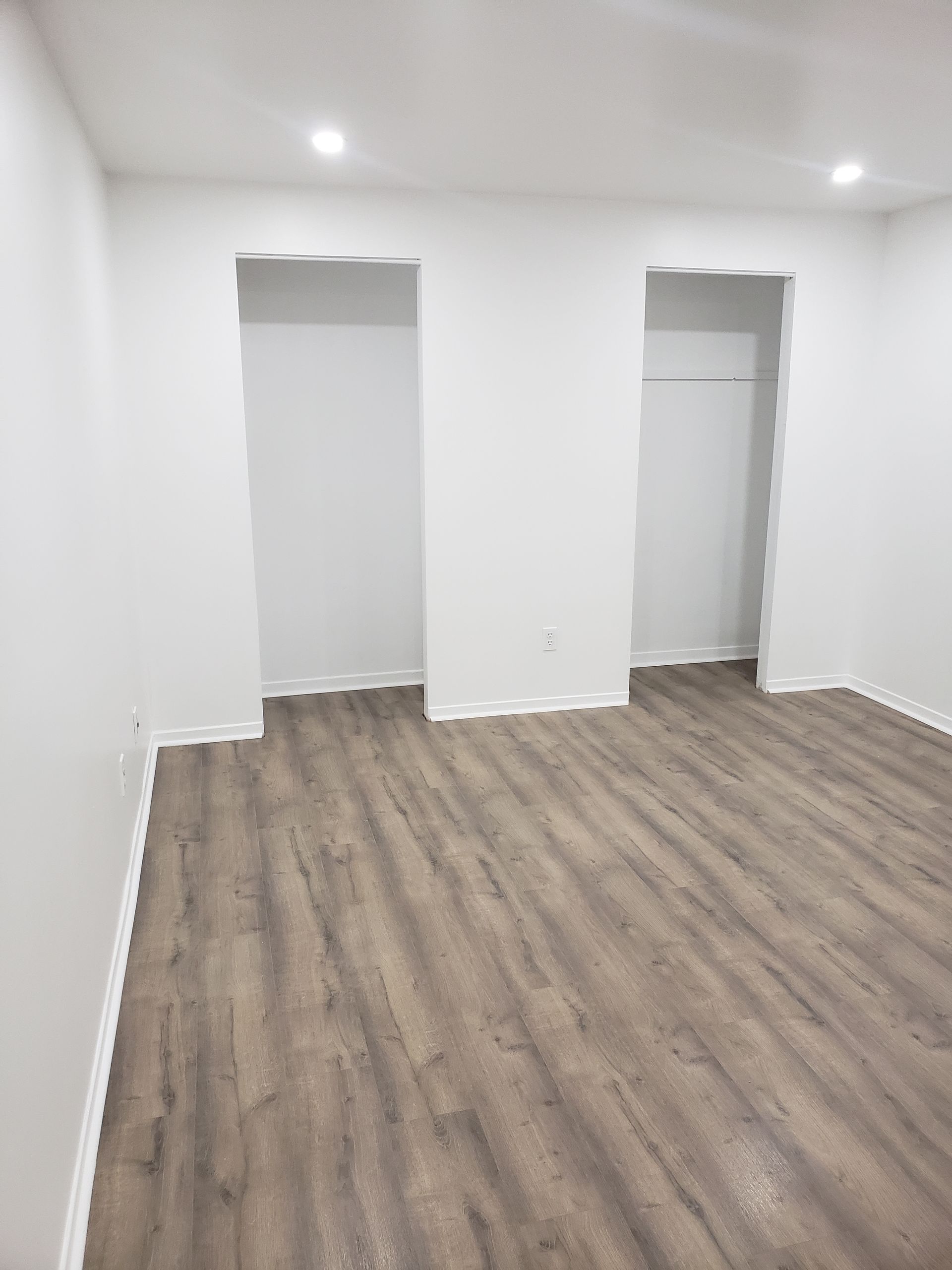 An empty room with hardwood floors and white walls.