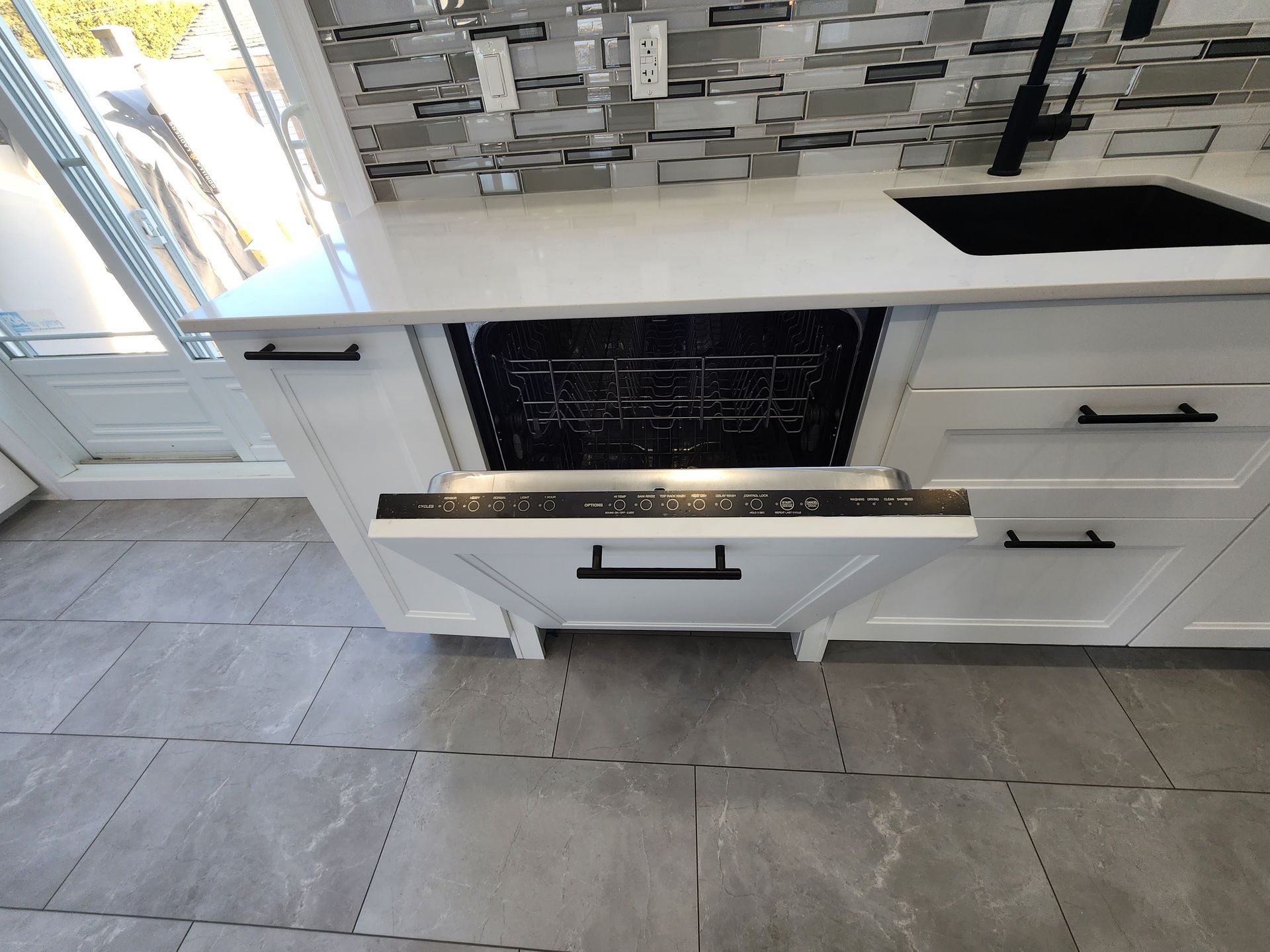 A kitchen with a sink and a dishwasher with the door open