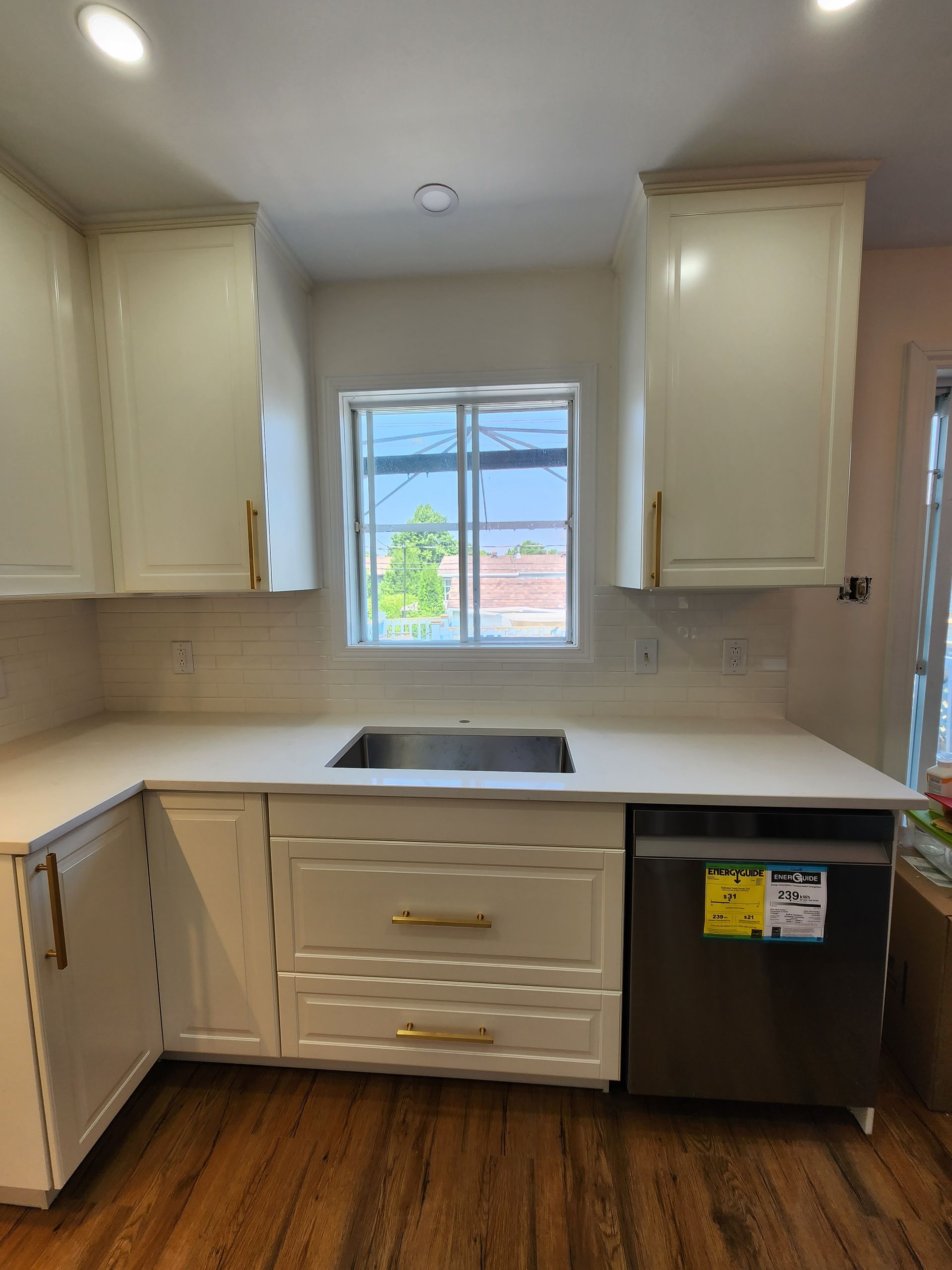 A kitchen with white cabinets and a black dishwasher