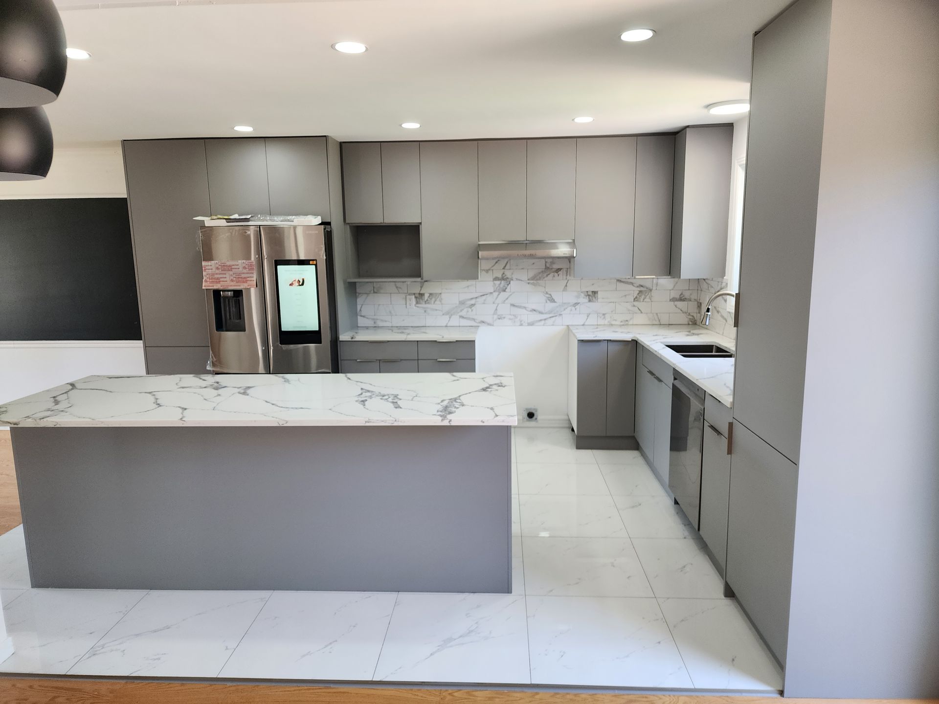 A kitchen with gray cabinets and a stainless steel refrigerator