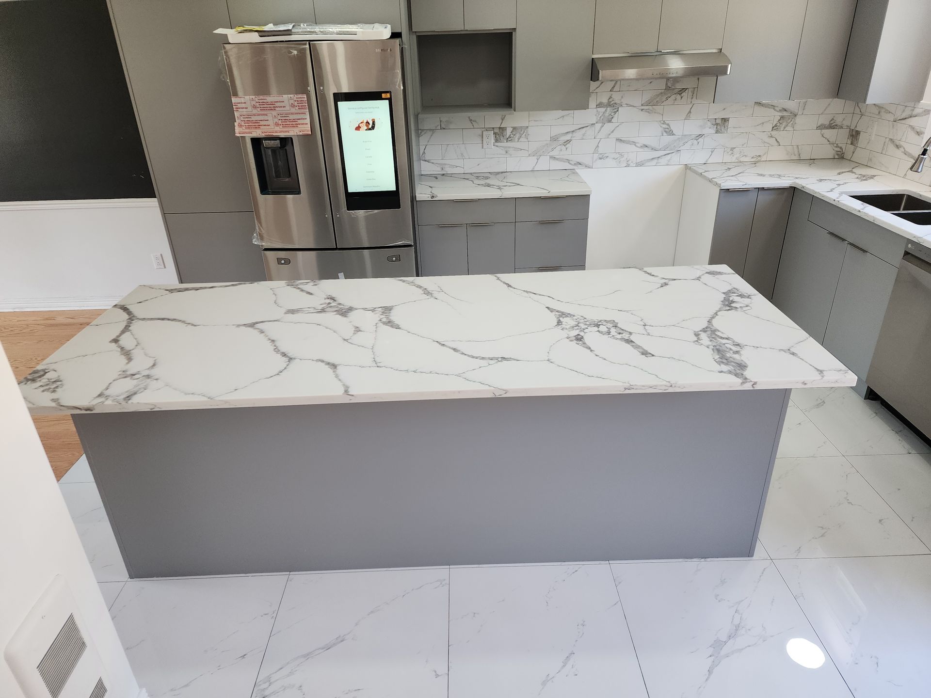 A kitchen with a marble counter top and a stainless steel refrigerator.