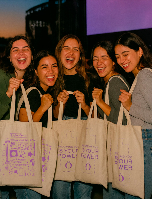 Five smiling people holding tote bags that say 