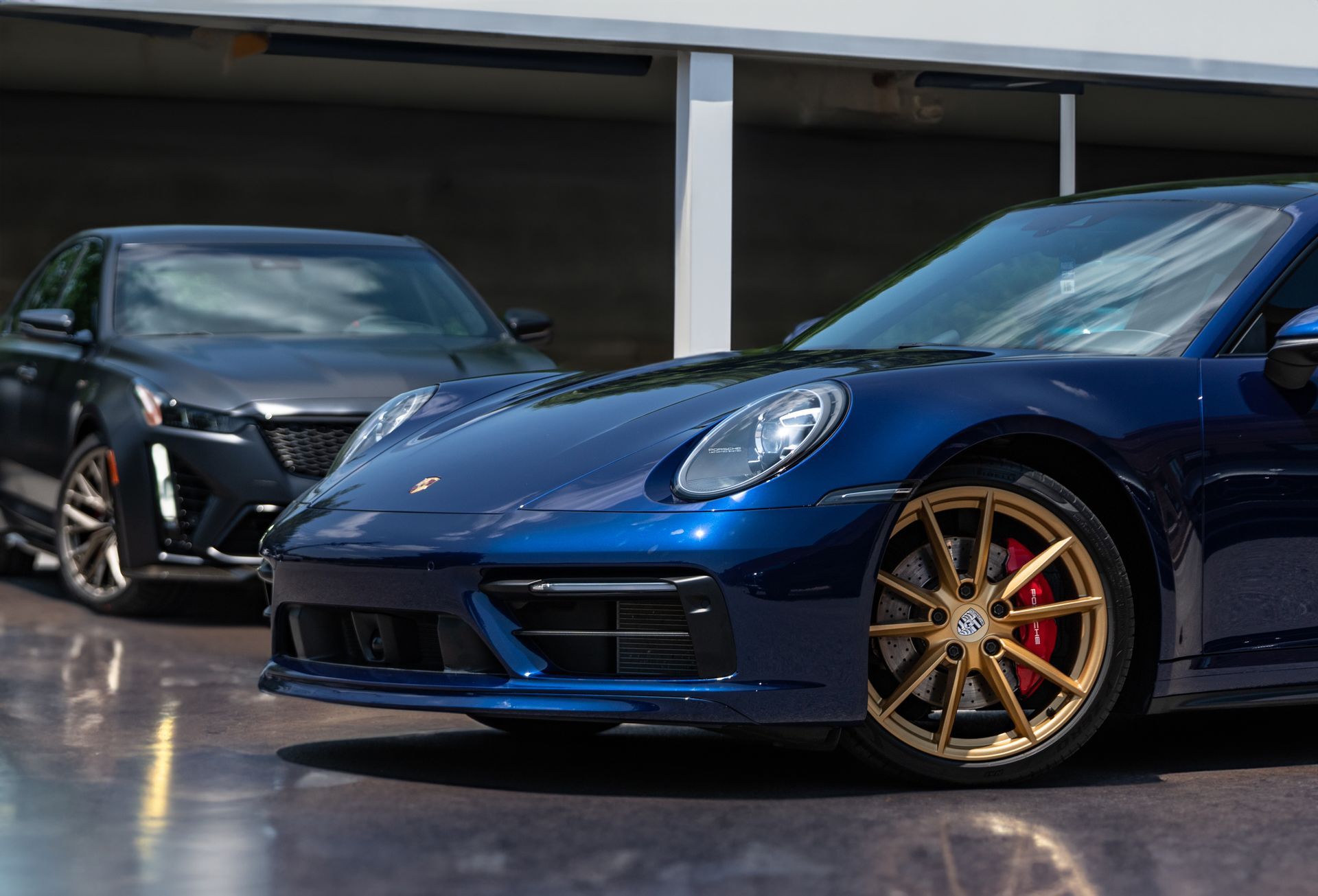 Two blue sports cars are parked next to each other in a garage.