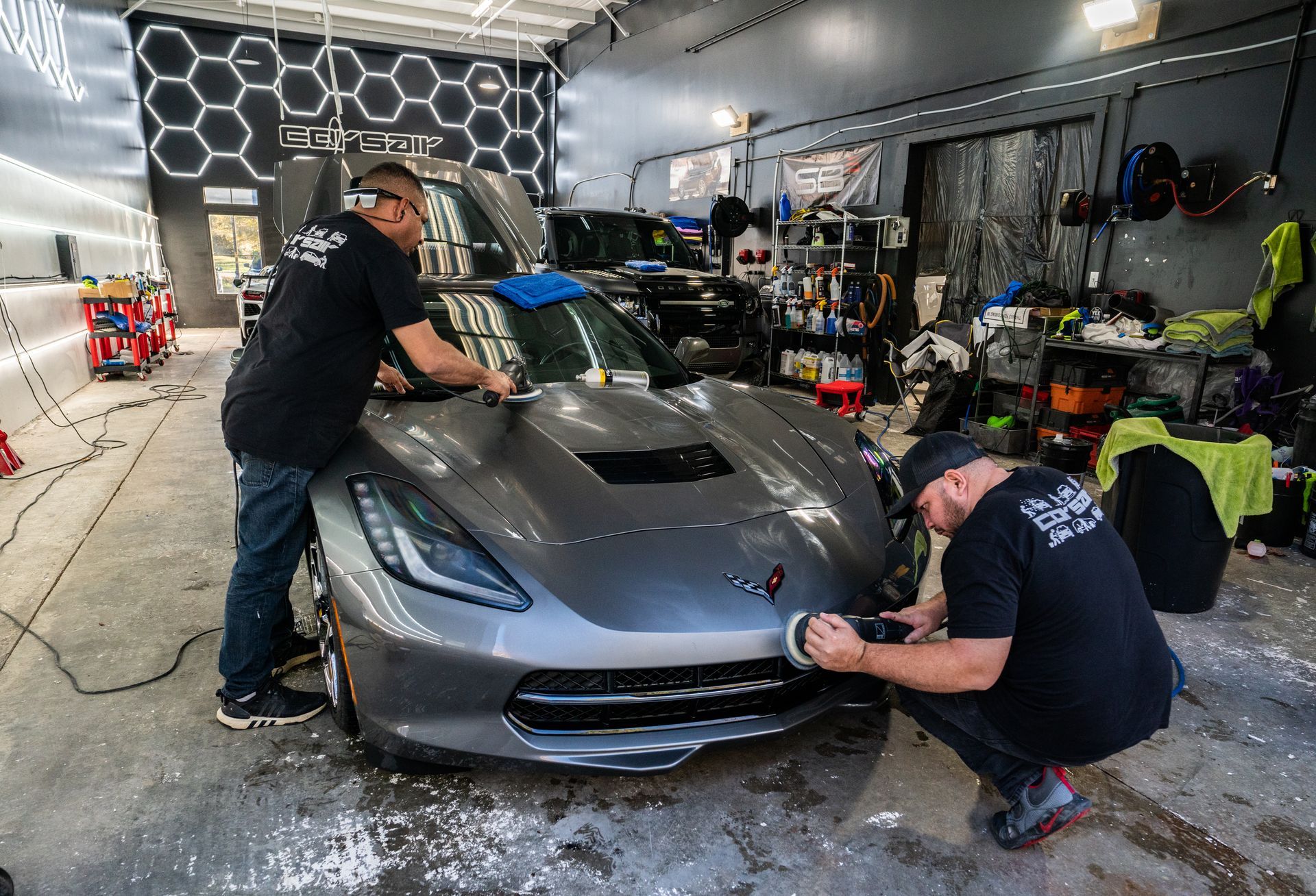 Two men are working on a car in a garage.