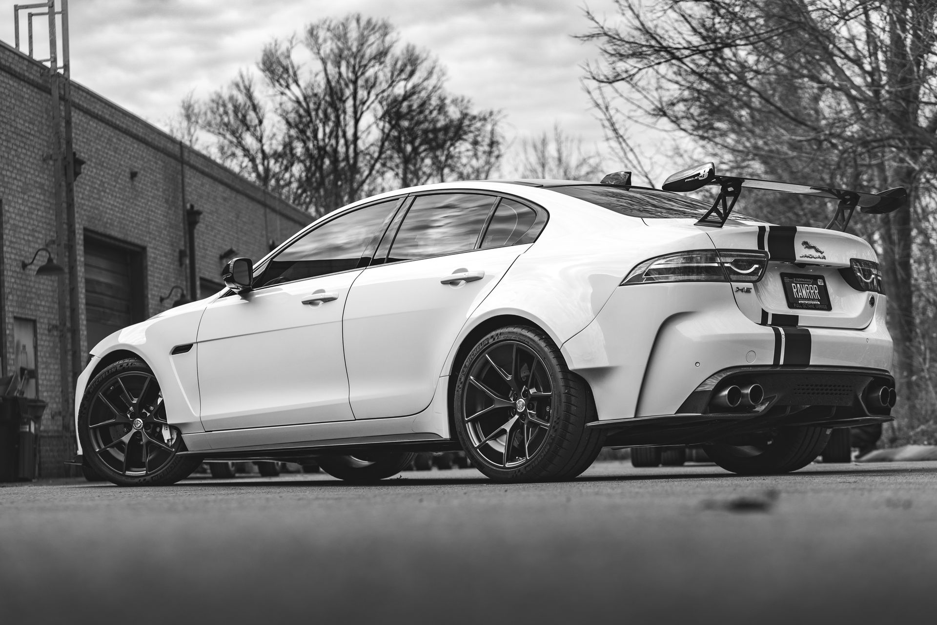 A black and white photo of a white car parked in front of a building.