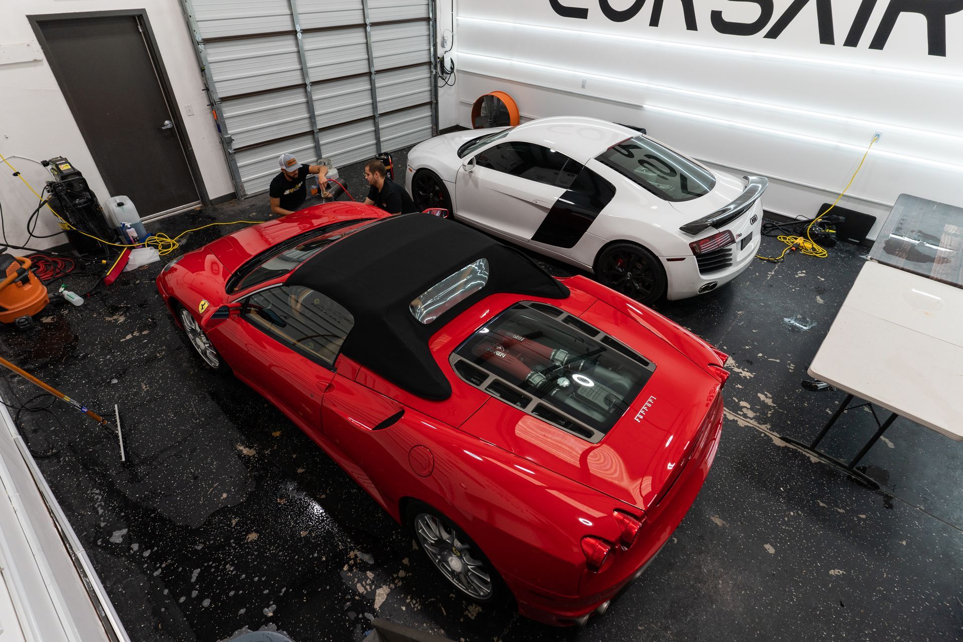 A red sports car and a white sports car are parked in a garage.