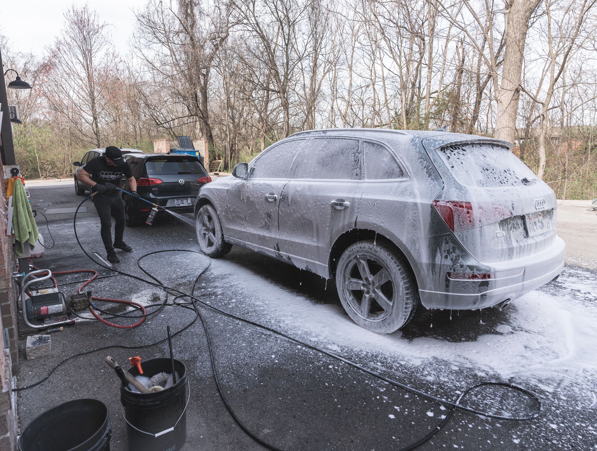 A man is washing a car with foam in a parking lot.