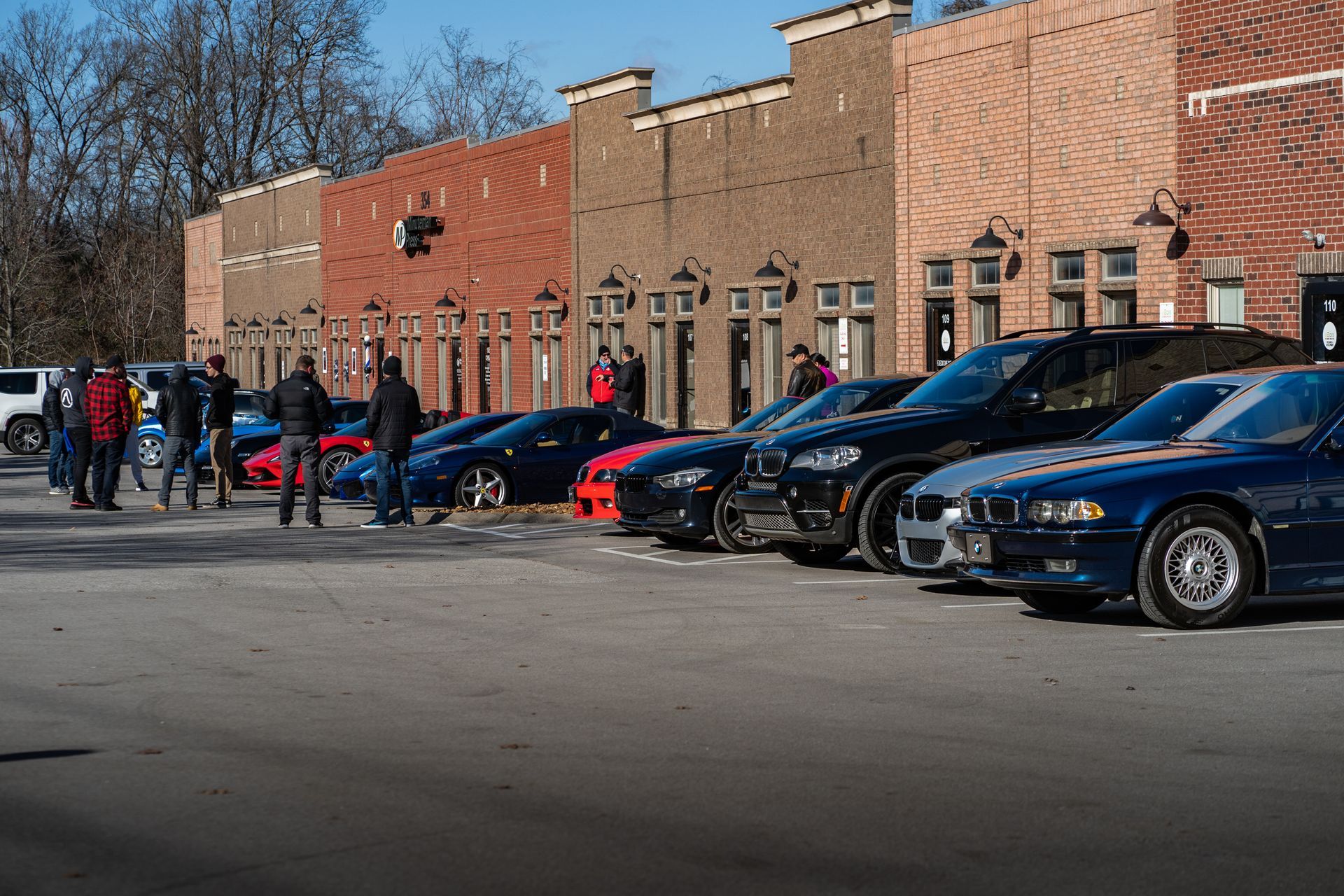 A row of cars are parked in front of a brick building.