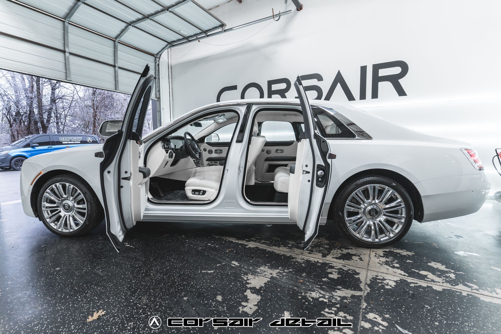 A white car is parked in front of a corsair sign
