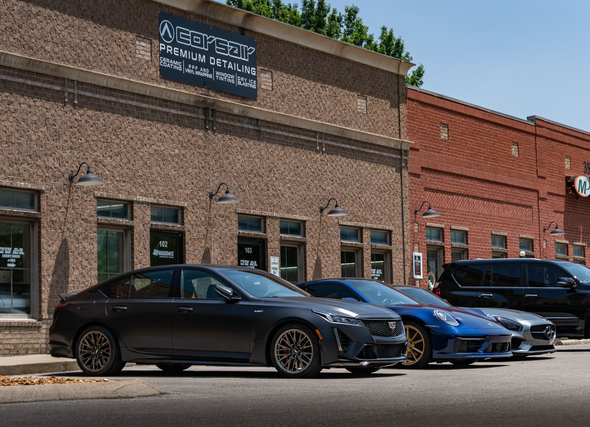 A row of cars are parked in front of a brick building.