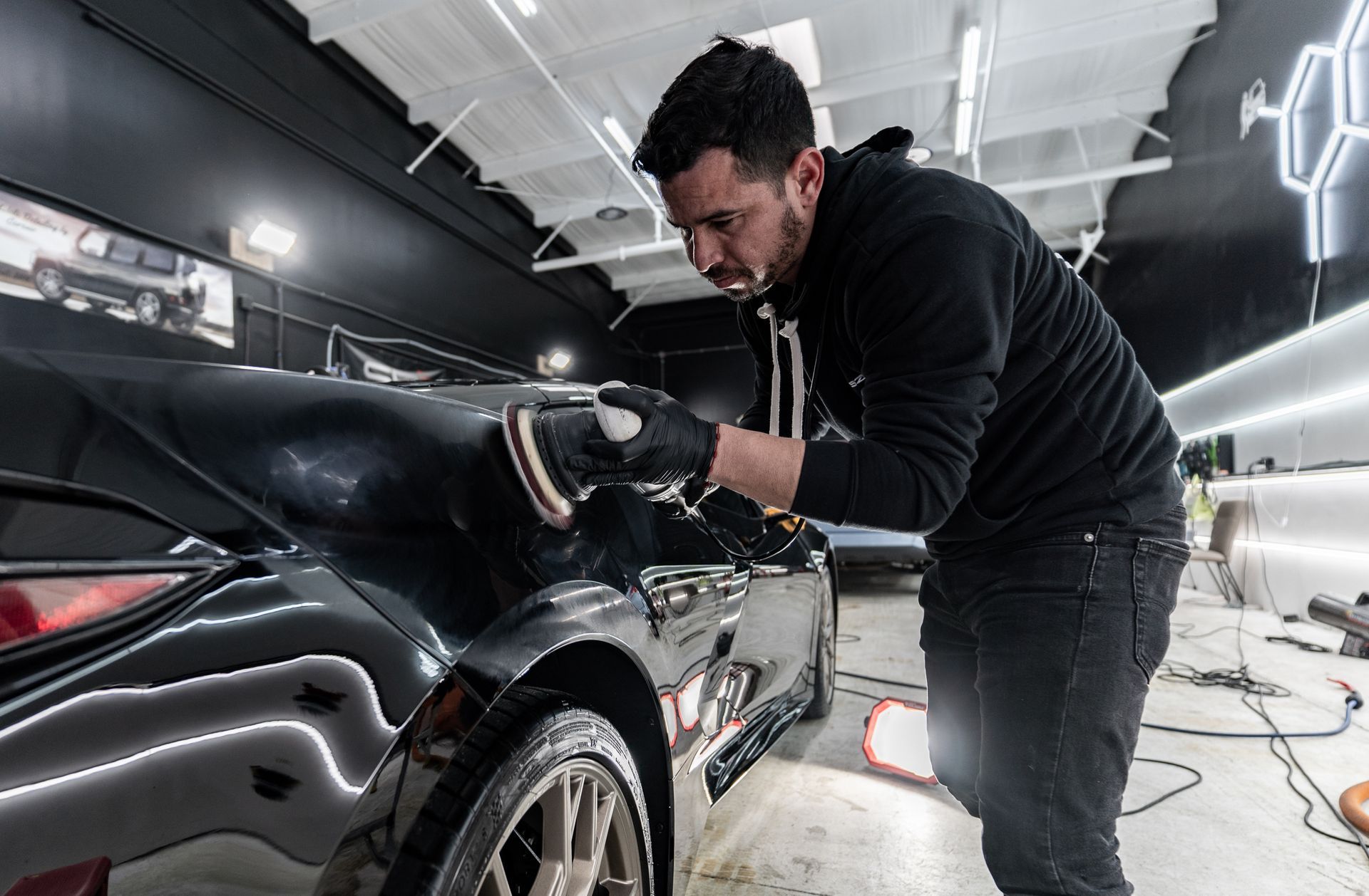 A man is polishing a car in a garage.