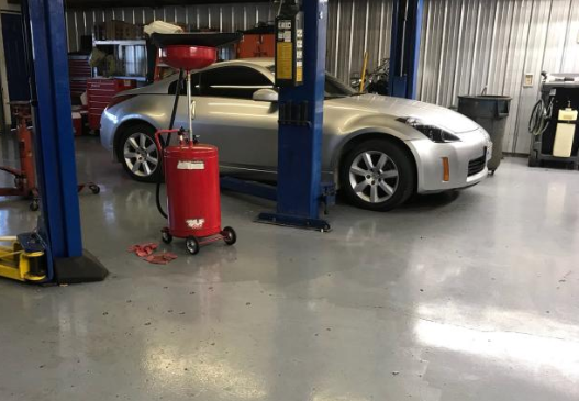 A silver car is parked on a lift in a garage. | A2Z AutosLLC