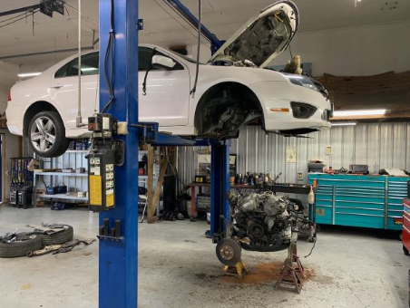 A white car is sitting on a lift in a garage. | A2Z AutosLLC