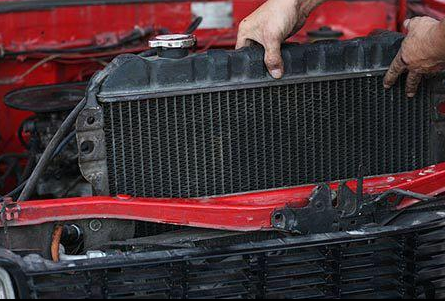 A person is removing a radiator from a car. | A2Z AutosLLC
