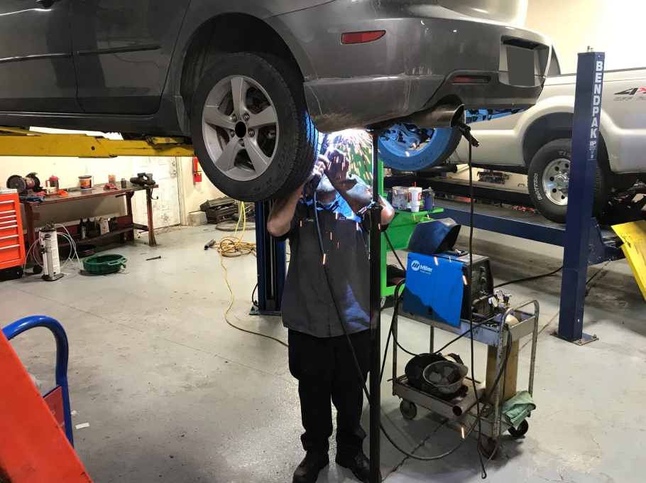 A man is working on a car on a lift in a garage. | A2z AutosLLC