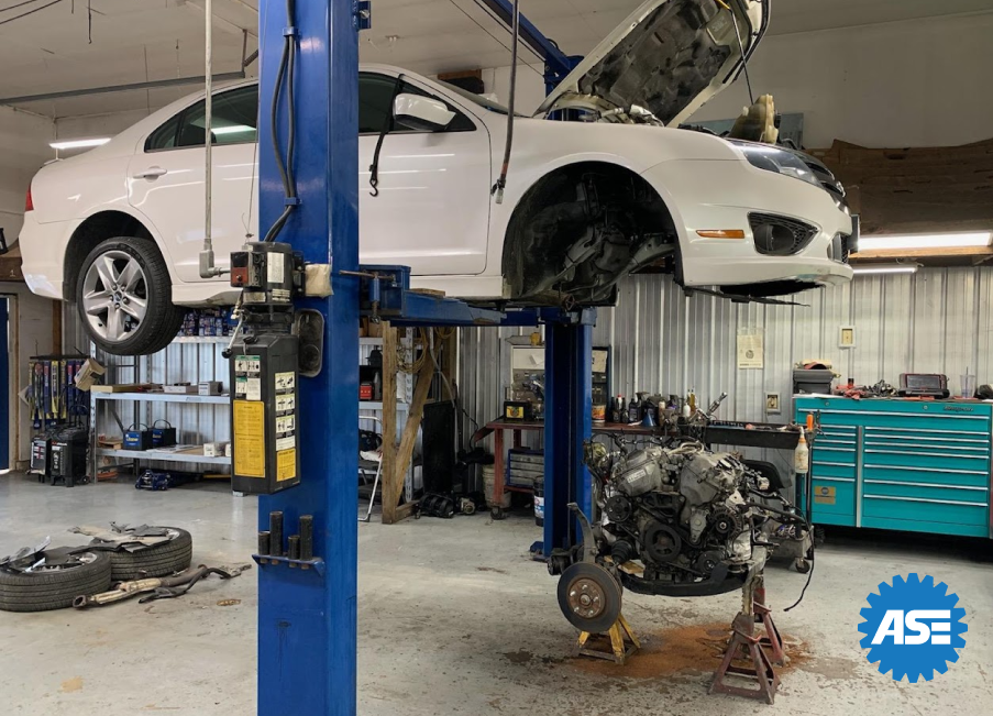 A white car is sitting on top of a blue lift in a garage. | A2z AutosLLC