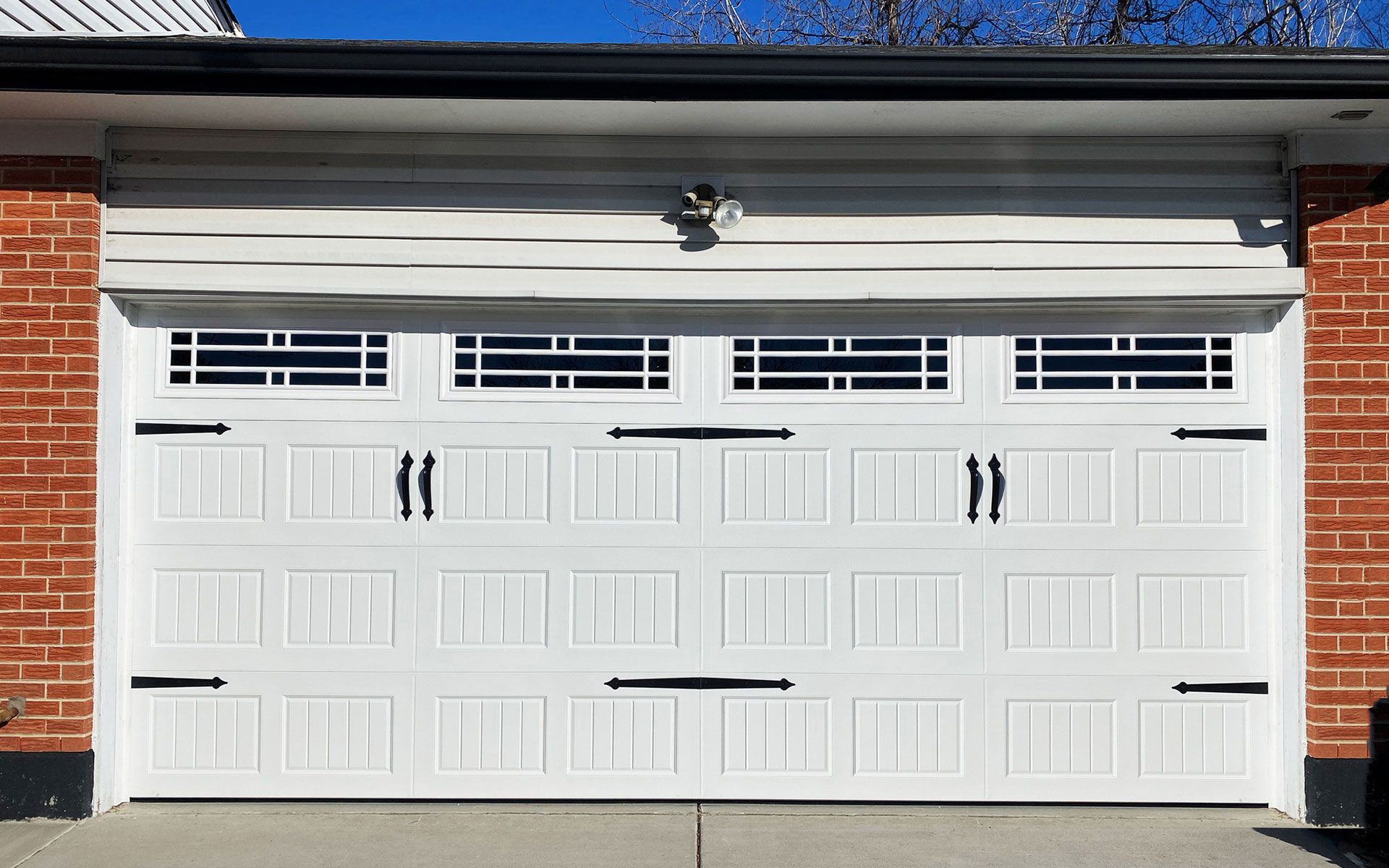 A white garage door is open on a brick house.