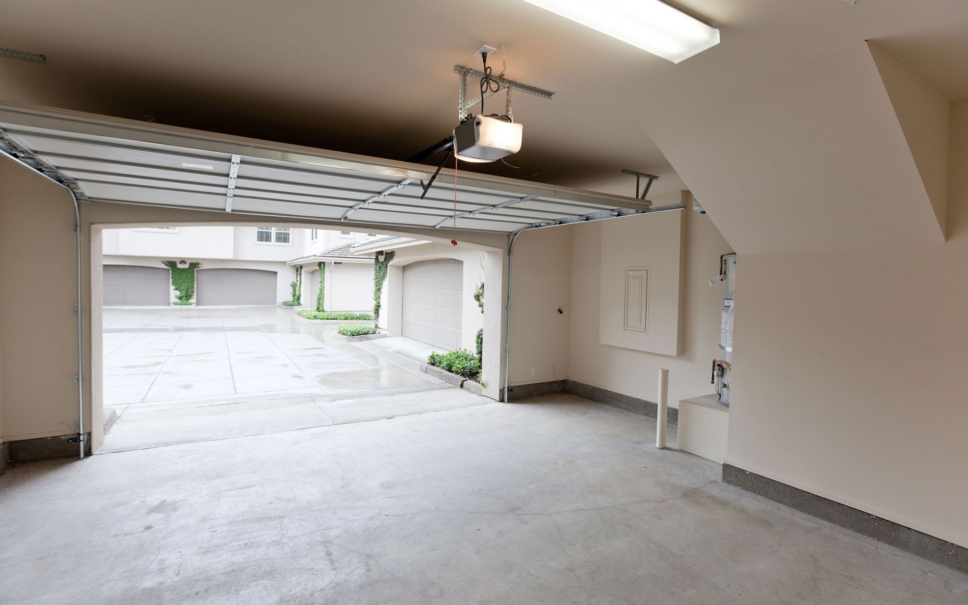An empty garage with a garage door open and a light on the ceiling.