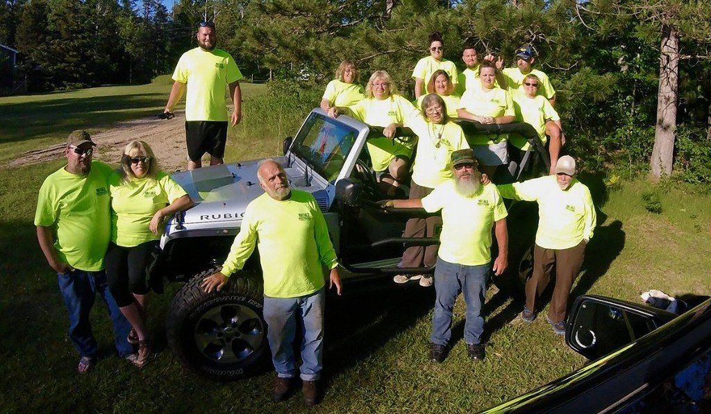 a group of people are posing for a picture in front of a jeep .