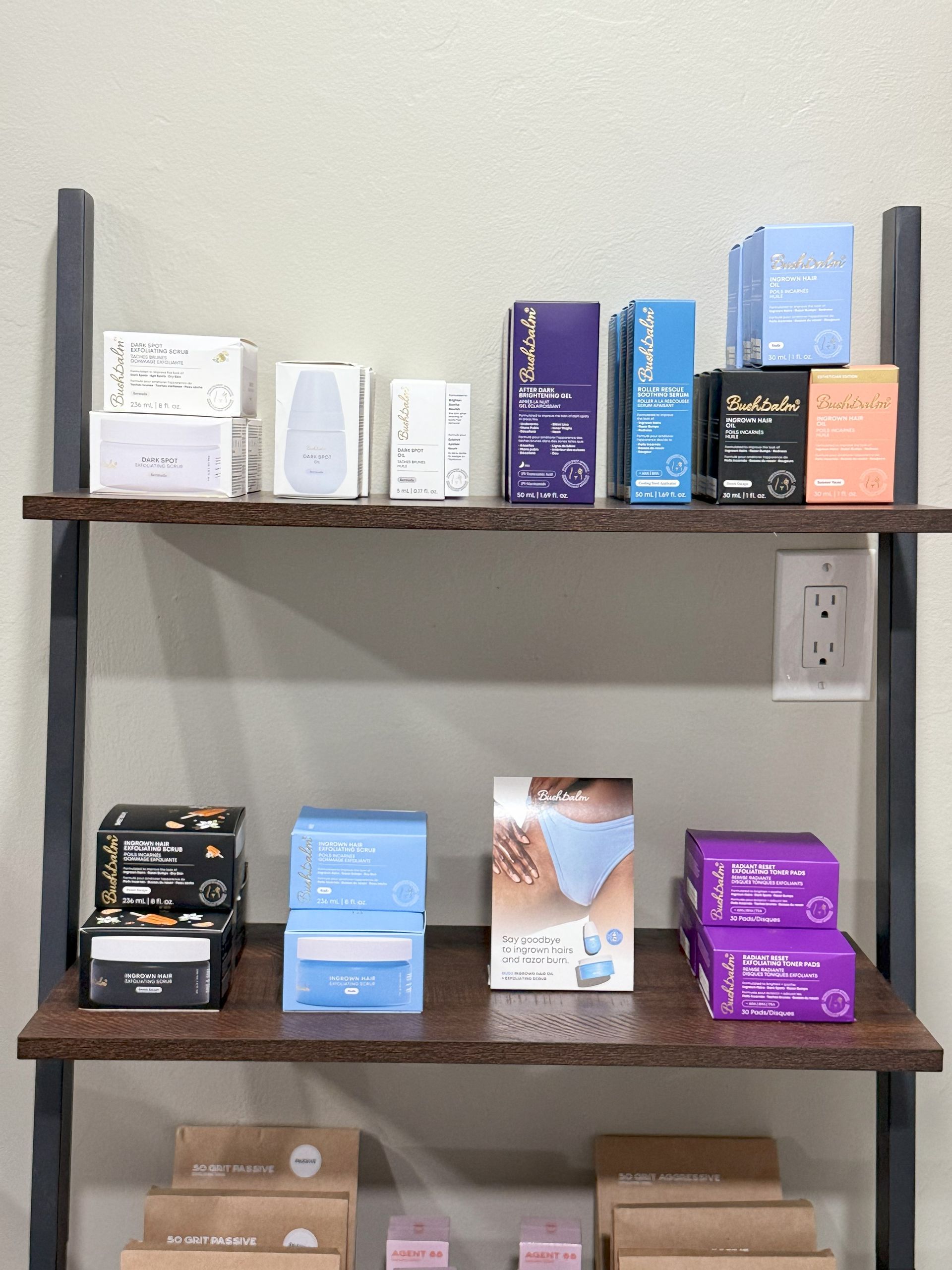 Shelves displaying various boxes of products, featuring a power outlet on the wall.